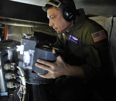 MSgt. David Dines reloads the film magazine on a panoramic camera Jan. 16, 2010, while flying over Haiti on an OC-135B observation aircraft. Air Force photo by SrA. Perry Aston.
