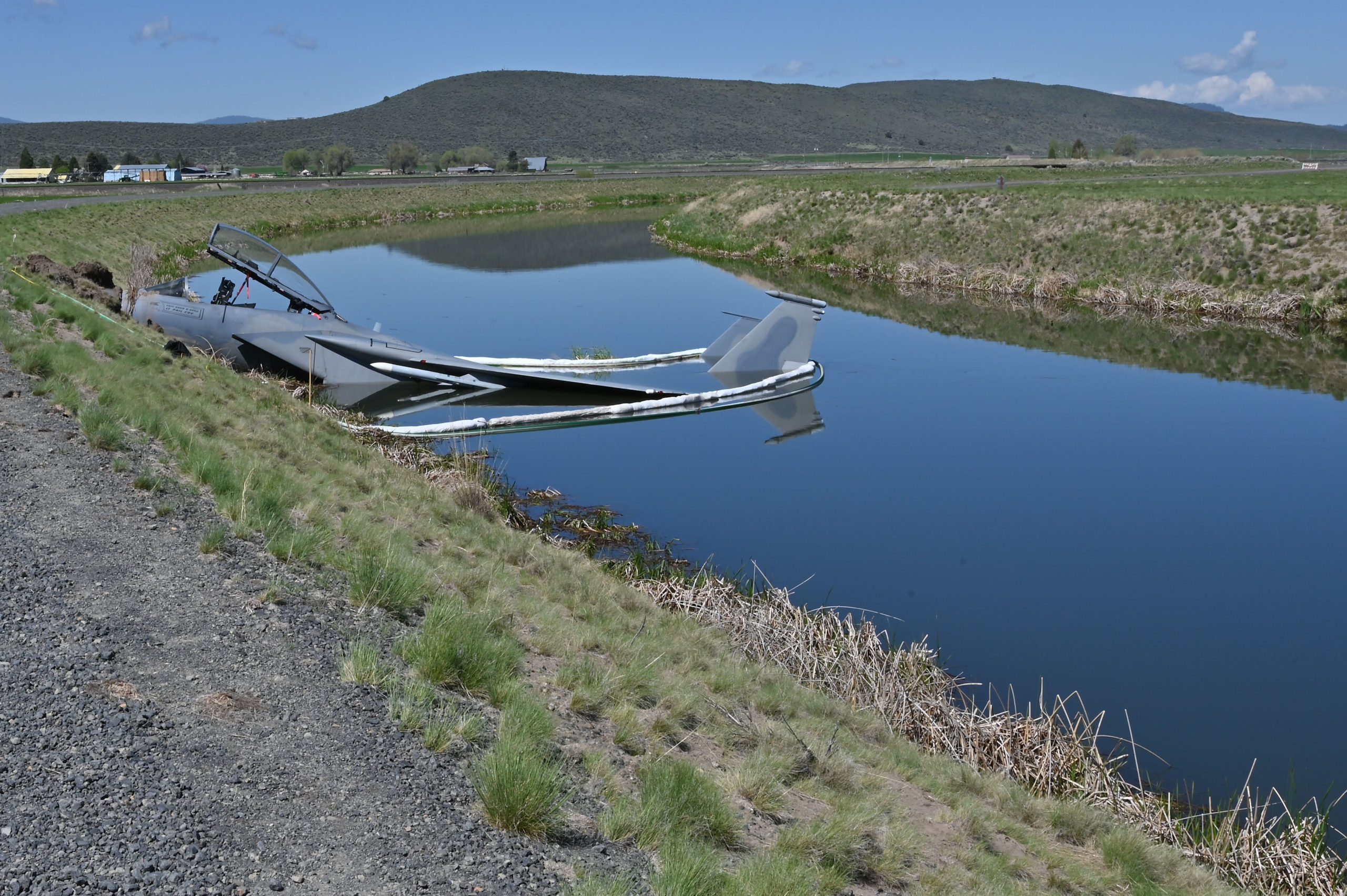 A U.S. Air Force F-15D assigned to the 173rd Fighter Wing sits in a Bureau of Reclamation canal on the south side of the runway following a mishap landing at Kingsley Field in Klamath Falls, Oregon May 15, 2023.